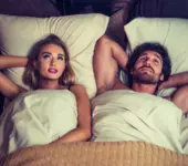 Couple lying in bed relaxing after intimacy, symbolizing anal aftercare and recovery, calm and comfortable atmosphere.